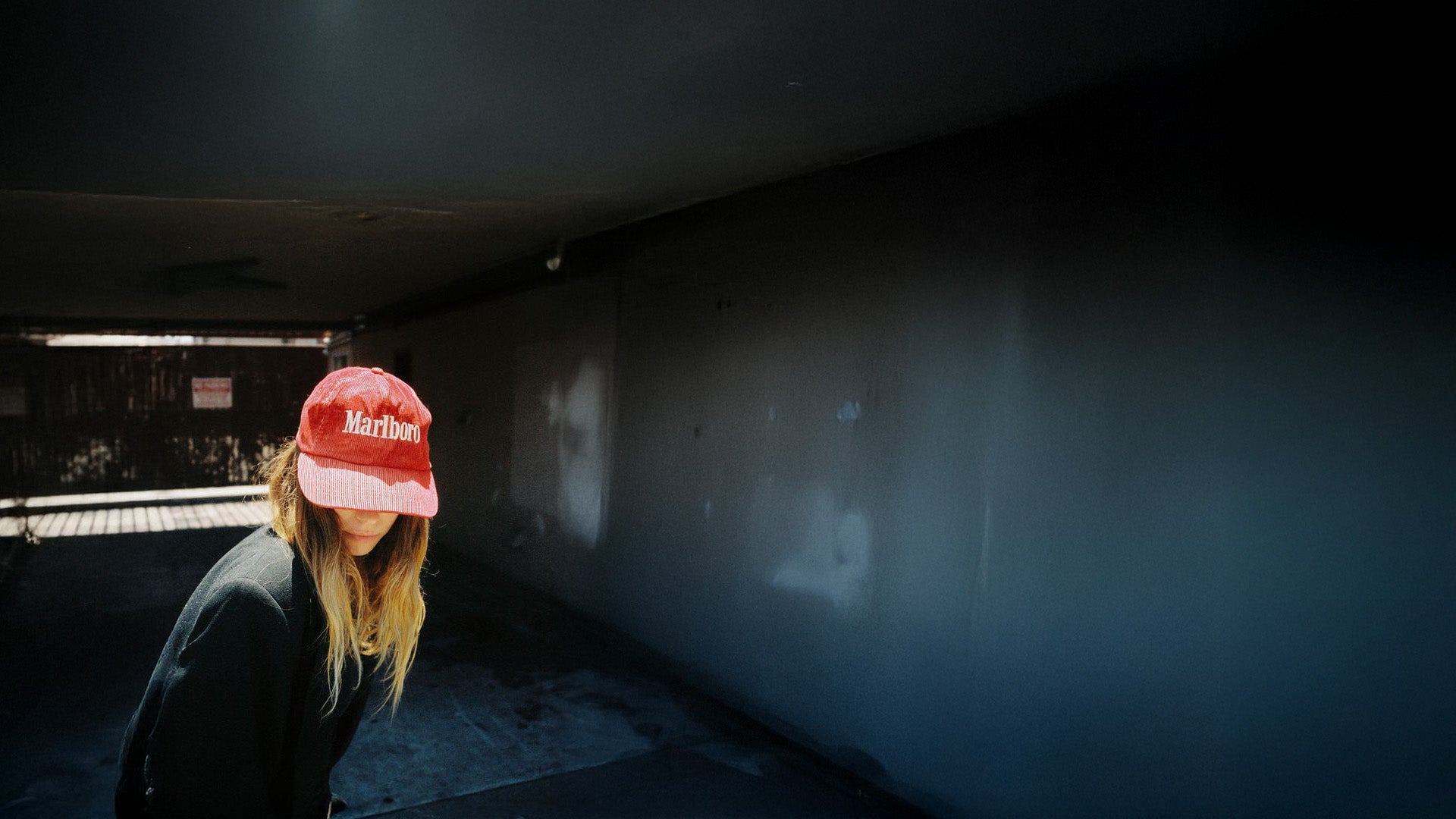 Person wearing a red cap with 'Marlboro' logo in a dark, industrial setting